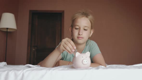 Girl Putting Coin in Piggy Bank Saving Money Concept