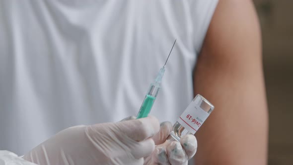 Closeup Detail of Doctor in Rubber Gloves Holding Syringe and Bottle with Vaccine Going Make