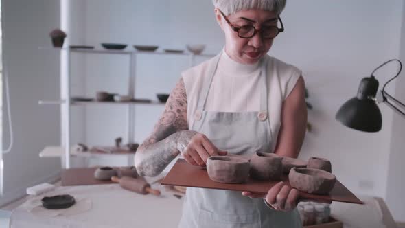 Asian elderly woman enjoying pottery work at home.