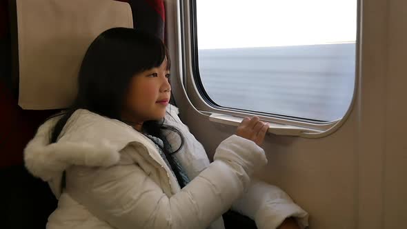 Little Asian Girl Looking Through Window. She Travels On A Train Slow Motion