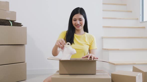Happy mother while unpacking carton box  and surprise with children's clothing