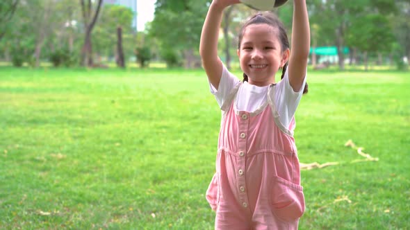 Smiling little girl standing holding the soccer ball at green football field in summer day