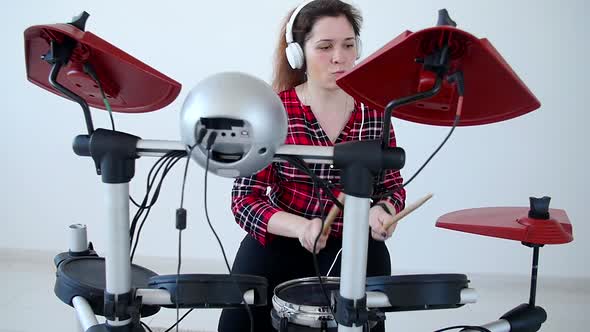 Concept of Hobby and Music. Young Woman Drummer Practicing Electronic Drum Kit at Home