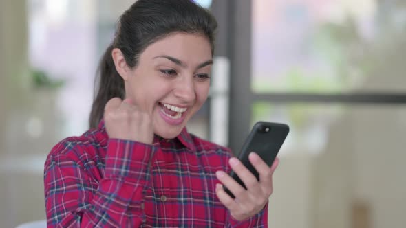 Young Indian Woman Celebrating Success on Smartphone