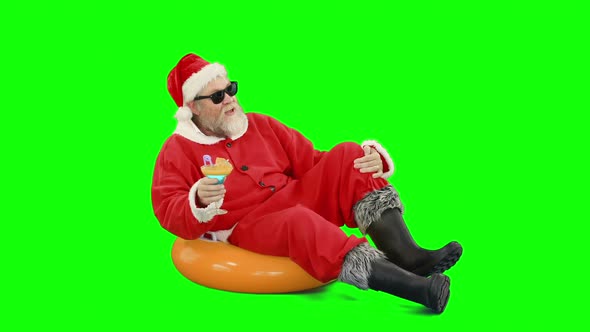 Santa claus sitting on inflatable tube and having cocktail