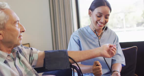 Animation of happy biracial female doctor checking pressure to caucasian senior man