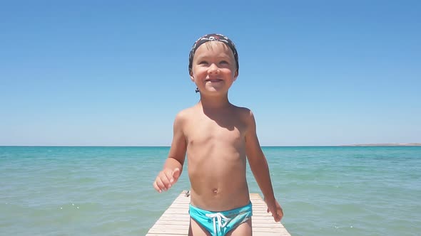 Baby Baby with Blue Eyes Smiling Posing for the Camera Against the Background of the Azure Sea and