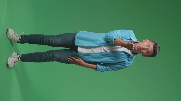 Full Body Of A Smiling Young Asian Boy Blowing Kisses To A Camera In The Green Screen Studio