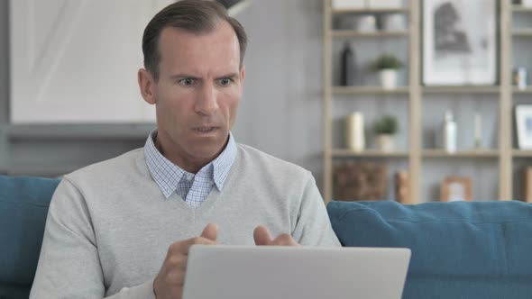 Shocked Middle Aged Man Wondering for Results on Laptop