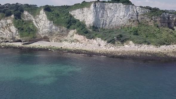 Flying towards the cliffs of Seaton beach in England. Rock formation and boulders are visible on the