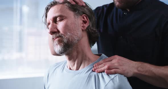 Crop Therapist Stretching Neck of Middle Aged Man