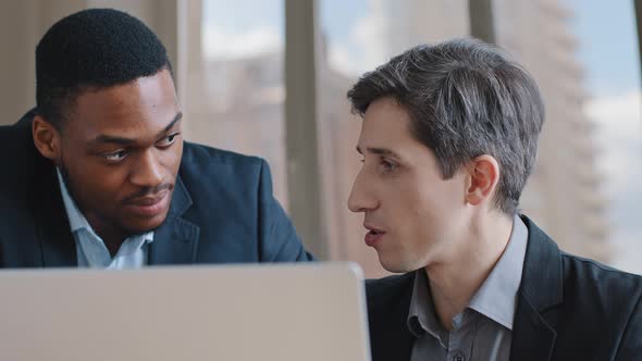 Two Confident Serious Male African Man and Caucasian Colleagues Business Men Reviewing Data in
