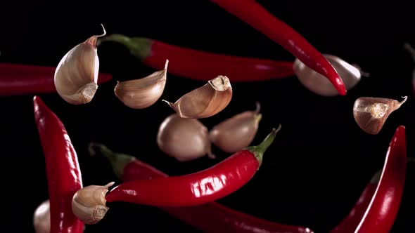 Super Slow Motion Shot of Flying Red Chilli Peppers and Garlic