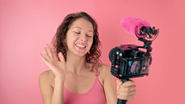 Young Woman Vlogger Recording Broadcast in Slow Motion on a Pink Background