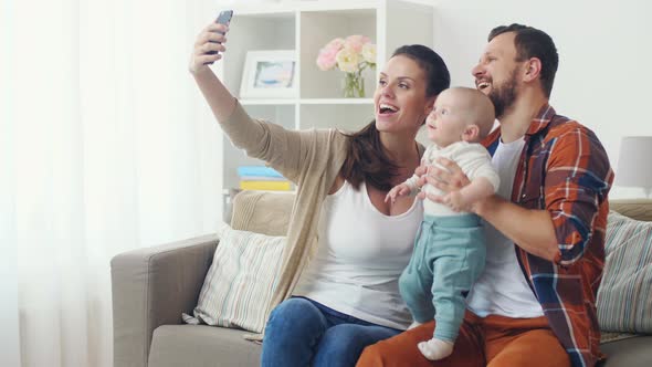 Mother and Father with Baby Taking Selfie at Home 