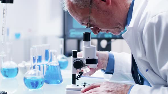 Close Up Shot of Researcher in His 60s Looking in a Microscope