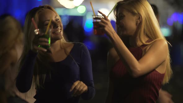 Happy Female Friends Enjoying Party on Dance Floor, Clanging Cocktail Glasses