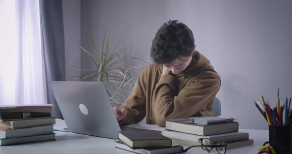 Brunette Caucasian Boy Moving Stiff Neck As Sitting at the Table with Laptop. Portrait of Male