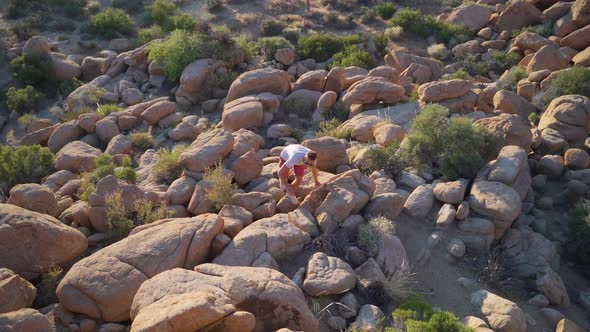 Man climbing up rocks in the desert, Joshua Tree national park, California, slow motion aerial