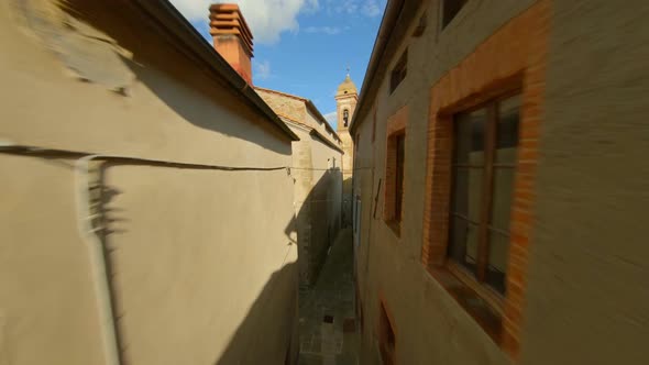 Drone Flying Through Narrow Alley Towards Bell Tower Of Collegiate Church Of San Biagio - Scrofiano,