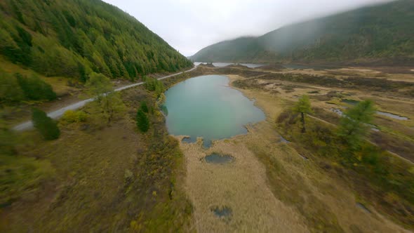 Aerial View White SUV Automobile Riding on Dirt Road Near Natural Forest and Mountain Lake Scenery