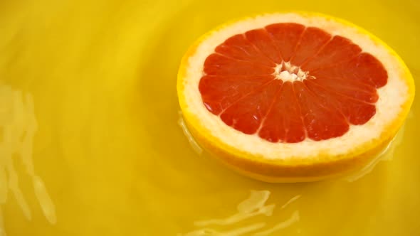 Rotating segment of ripe and juicy grapefruit on an orange background. Slow motion.