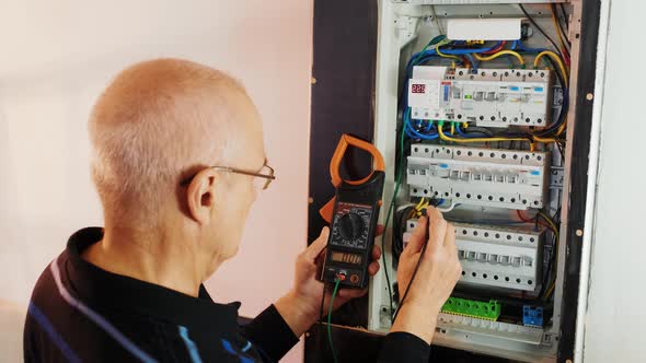 Electricians hands testing current  electric in control panel.