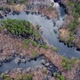 Aerial view of the river between the pines. Flying over a winding riverbed surrounded by treetops - VideoHive Item for Sale