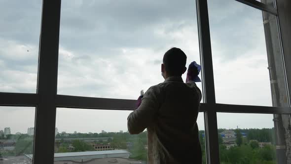 A handsome man cleaning the windows of his house from the inside