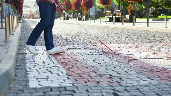 A Blind Man with a Cane Crosses the Road