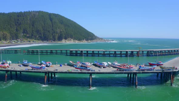 port or caleta meguellines, constitucion chile drone shot sunny day with fishing boats traveling lef