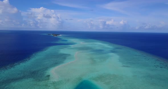 Daytime fly over clean view of a sunshine white sandy paradise beach and blue water background 