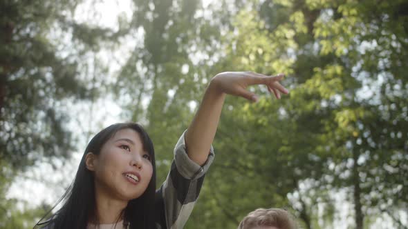 A Young Lovely Couple is Walking in the Public Park Looking Around and Talking to Each Other Smiling