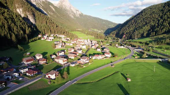 Aerial View of an Austrian Village in a Green Mountain Valley at Sunset Alps