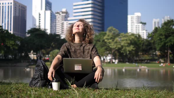 Happy Woman Working On Laptop Enjoying Sunshine In Park