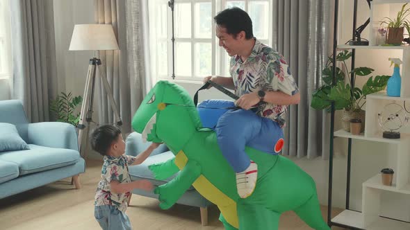 Asian Father Ride Dinosaur Toy With His Son In Modern House Living Room, Happy Family