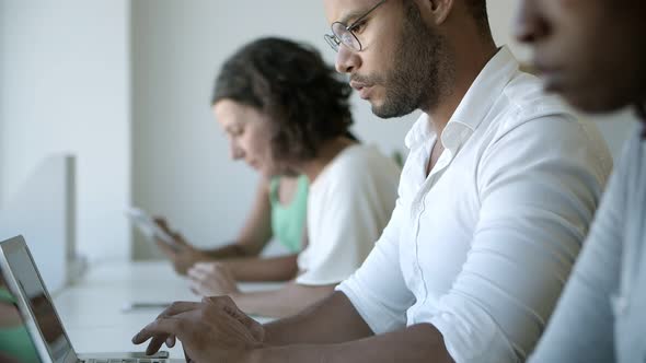 Focused African American Man in Eyeglasses Typing on Laptop