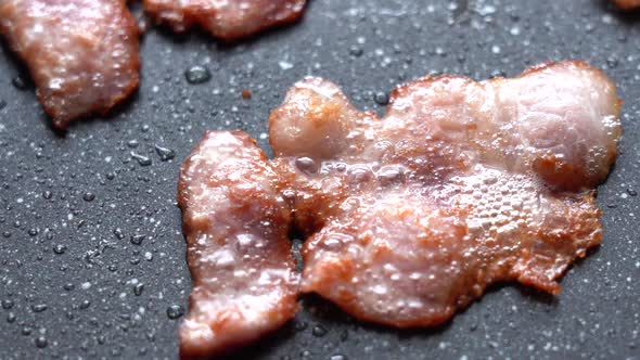 Crispy Pieces of Delicious Bacon are Fried in a Hot Pan