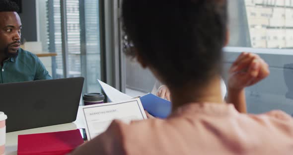 Diverse business people discussing with documents in creative office