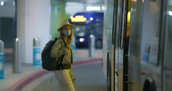 Woman in Face Mask Boarding the Bus Shuttle at the Arrival Area of Airport
