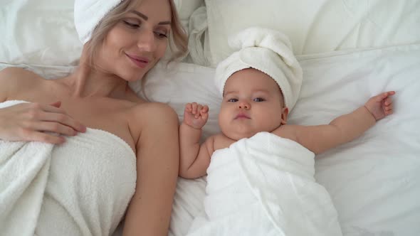 a Young Beautiful Mother of European Appearance is Lying in the Room on the Bed with a Newborn Baby