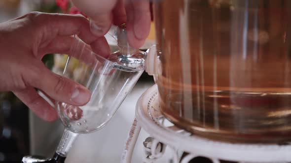 Man Ands Put Glass to Tap of Jar with Cocktail