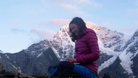 Lady Communicates Via Laptop Sitting on Hill Top and Smiles