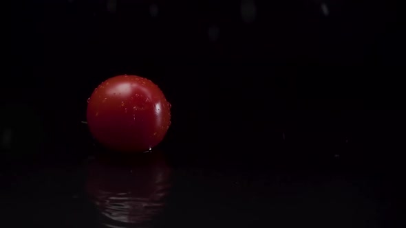 Cherry Tomatoes Falling on Water in Slow Motion with a Black Background