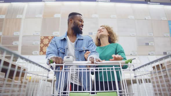 Low Angle View of Cheerful Young Diverse Couple Shopping in Hardware Store