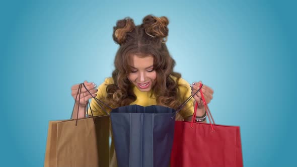 Beautiful Girl Looks in Shopping Bags After Shopping