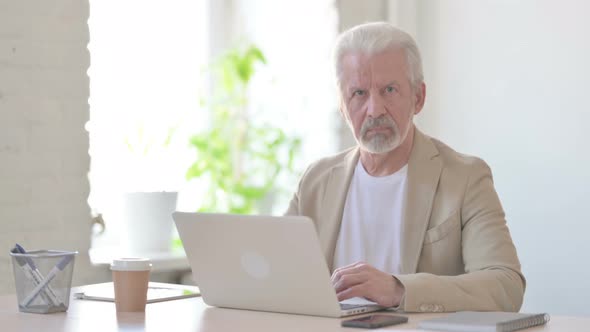 Old Man Shaking Head in Rejection While Using Laptop in Office