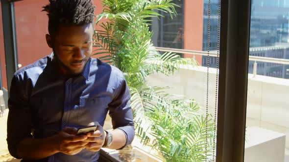 Front view of young black businessman using mobile phone in a modern office 4k
