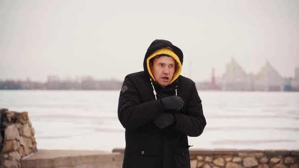 Young Frozen Man in Black Jacket Jumps From Cold Standing on Street