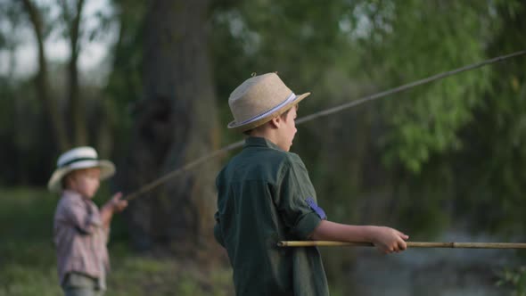 Children Fishermen Adorable Boy in Hat with His Little Brother Fishing with Wooden Rod While